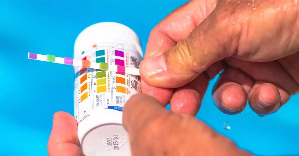 Man testing cyanuric acid levels in private swimming pool with easy test strip