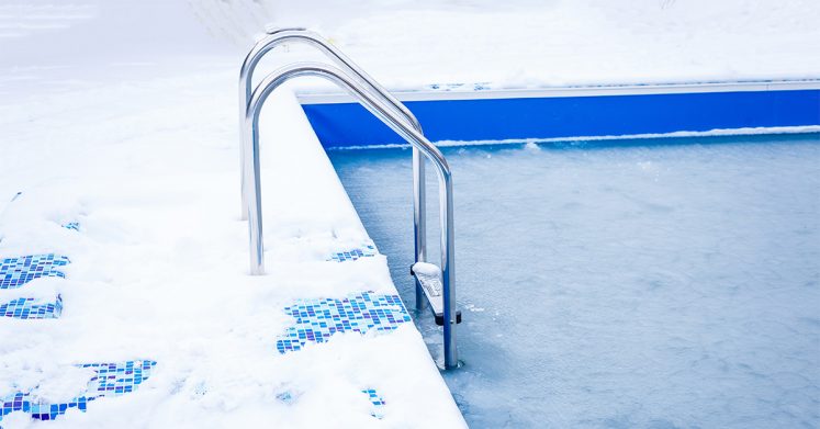 Frozen swimming pool with snow around it, in the winter
