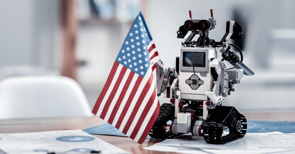 Lego robot on office desk, holding American flag. 4th of July decoration
