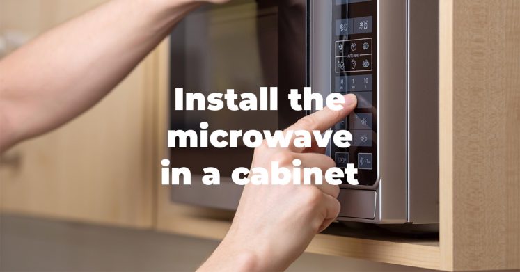 Microwave being installed in a cabinet
